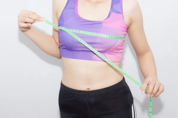 Žena v sportovní podprsenka měření její tělo s páskou izolovaných na Svatodušní — Stock fotografie