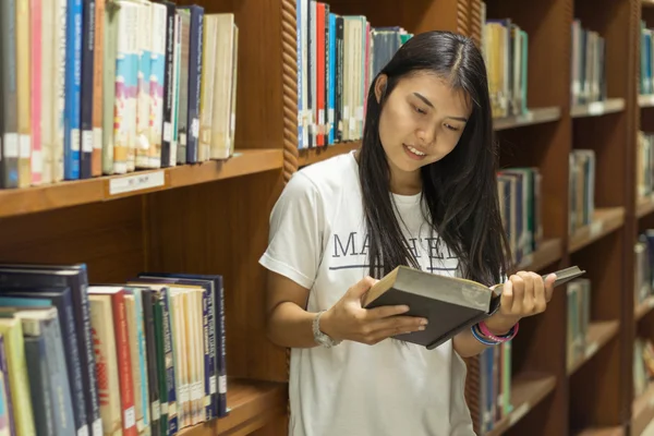 Portréja egy komoly fiatal diák, olvasson egy könyvet a könyvtárban — Stock Fotó