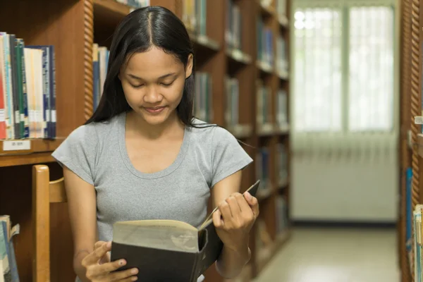 kitaplığındaki kitap okuyarak ciddi, genç bir öğrenci portresi