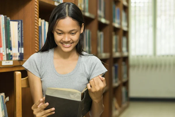 Porträtt av en allvarlig ung student som läser en bok i ett bibliotek — Stockfoto