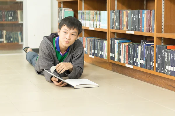 Retrato de um jovem estudante sério lendo um livro em uma biblioteca — Fotografia de Stock