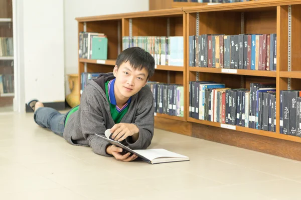 Retrato de un joven estudiante serio leyendo un libro en una biblioteca —  Fotos de Stock