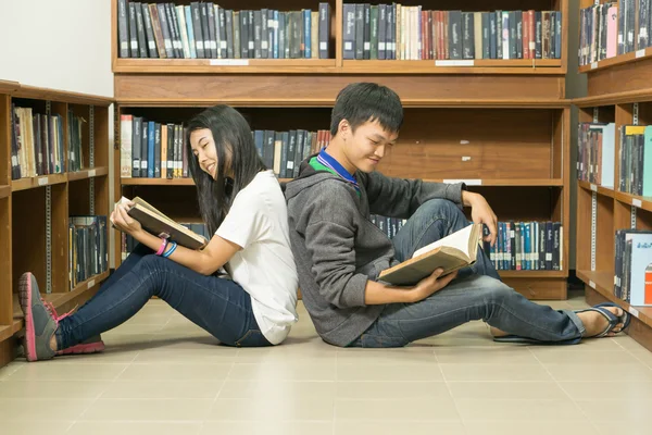 Portréja egy komoly fiatal diák, olvasson egy könyvet a könyvtárban — Stock Fotó