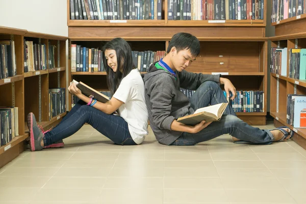Портрет серьезного молодого студента, читающего книгу в библиотеке — стоковое фото