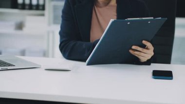 Modern ofiste dizüstü bilgisayarla çalışan genç bir iş kadını.