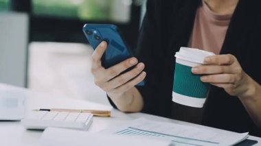 Ofiste akıllı telefonla çalışan genç bir iş kadını..