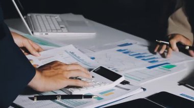 İş adamı masadaki mali verileri hesaplamak için bir hesap makinesi kullanıyor.