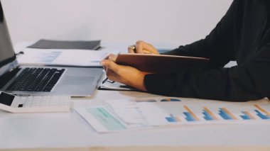 Bilgisayarda çalışan iş kadınlarını kapatın ve bilgisayardaki verilerle grafiği analiz edin.