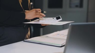 İşletme ekibi ofisteki bir laptopta finansal grafikleri ve grafikleri tartışıyor..