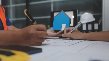 Dizüstü bilgisayar üzerinde çalışan ve çalışan mühendis veya mühendis veya mühendis veya mühendis veya mühendis, arka planda ev ya da plan ve inşaat alanlarıyla birlikte plan üzerinde çalışıyor.