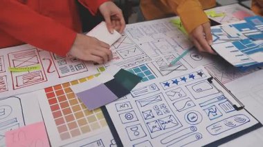 Cep telefonu kullanan ve kağıt üzerine renk paleti çizen kadın tasarımcı