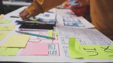 Ofiste dizüstü bilgisayarla çalışan genç bir iş kadını, bir deftere yazıyor..