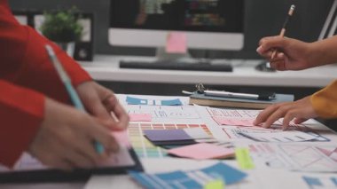 Genç tasarımcı kadın yeni projeyle çalışıyor ve masadaki rengi dizüstü bilgisayarla seçiyor