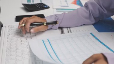 İş kadını ofisteki hesap makinesindeki mali verileri analiz ediyor.