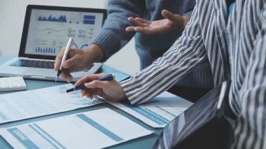 İş görüşmeleri sırasında grafiği analiz eden ve laptop kullanan işadamlarının yakın plan görüntüsü.