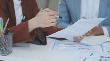 Elinde hesap makinesi olan bir iş kadını, ofiste çalışan iş adamları.