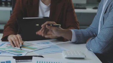 İş adamları mali verileri tartışıyor ve ofiste beyin fırtınası yapıyorlar.