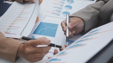 İş adamının kalem tutuşu ve ofisteki tabloya işaret edişinin yakın görüntüsü