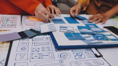 Uxui tasarımcılarından oluşan bir ekip bilgisayar ekranını işaret ederek ofiste yeni mobil uygulama tasarımını tartışıyor.