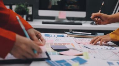 Uxui tasarımcılarından oluşan bir ekip bilgisayar ekranını işaret ederek ofiste yeni mobil uygulama tasarımını tartışıyor.