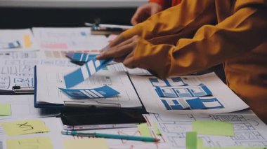 Uxui tasarımcılarından oluşan bir ekip bilgisayar ekranını işaret ederek ofiste yeni mobil uygulama tasarımını tartışıyor.