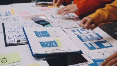 Uxui tasarımcılarından oluşan bir ekip bilgisayar ekranını işaret ederek ofiste yeni mobil uygulama tasarımını tartışıyor.
