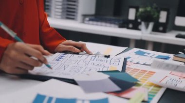 Uxui tasarımcılarından oluşan bir ekip bilgisayar ekranını işaret ederek ofiste yeni mobil uygulama tasarımını tartışıyor.