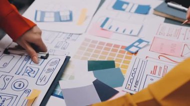 Uxui tasarımcılarından oluşan bir ekip bilgisayar ekranını işaret ederek ofiste yeni mobil uygulama tasarımını tartışıyor.