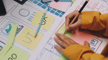 Uxui tasarımcılarından oluşan bir ekip bilgisayar ekranını işaret ederek ofiste yeni mobil uygulama tasarımını tartışıyor.