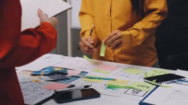 Uxui tasarımcılarından oluşan bir ekip bilgisayar ekranını işaret ederek ofiste yeni mobil uygulama tasarımını tartışıyor.