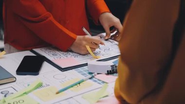 Uxui tasarımcılarından oluşan bir ekip bilgisayar ekranını işaret ederek ofiste yeni mobil uygulama tasarımını tartışıyor.