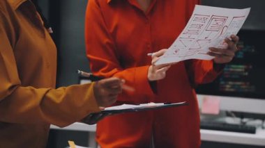 Uxui tasarımcılarından oluşan bir ekip bilgisayar ekranını işaret ederek ofiste yeni mobil uygulama tasarımını tartışıyor.