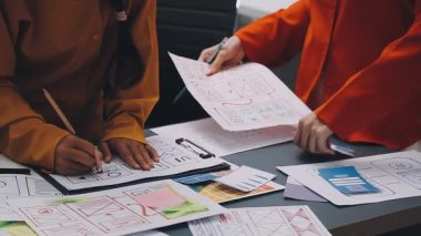 Uxui tasarımcılarından oluşan bir ekip bilgisayar ekranını işaret ederek ofiste yeni mobil uygulama tasarımını tartışıyor.