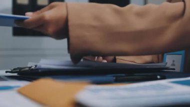 Finans belgesi ve mali muhasebe kavramının rakamlarını hesaplamak için hesap makinesi kullanan bir iş kadını