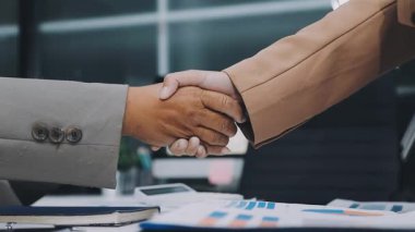 Genç iş adamları ofiste el sıkışıyor. Başarılı toplantı sona eriyor. Üç kişi