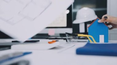 Mimarlar takımı, mühendisler mimari planları gözden geçirmek için birlikte çalışıyorlar. Planları inceliyor, bina planlarını not alıyor. Ofis ortamında olması muhtemel. Tasarım projesi için işbirliği anahtarı. Resim