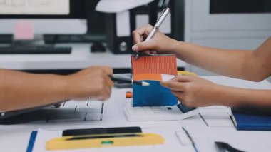 Mimarlar takımı, mühendisler mimari planları gözden geçirmek için birlikte çalışıyorlar. Planları inceliyor, bina planlarını not alıyor. Ofis ortamında olması muhtemel. Tasarım projesi için işbirliği anahtarı. Resim