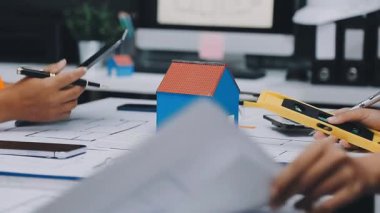 Mimarlar takımı, mühendisler mimari planları gözden geçirmek için birlikte çalışıyorlar. Planları inceliyor, bina planlarını not alıyor. Ofis ortamında olması muhtemel. Tasarım projesi için işbirliği anahtarı. Resim