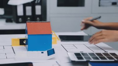 Mimarlar takımı, mühendisler mimari planları gözden geçirmek için birlikte çalışıyorlar. Planları inceliyor, bina planlarını not alıyor. Ofis ortamında olması muhtemel. Tasarım projesi için işbirliği anahtarı. Resim