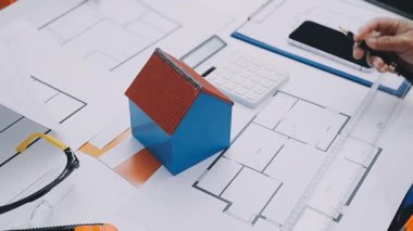 Mimarlar takımı, mühendisler mimari planları gözden geçirmek için birlikte çalışıyorlar. Planları inceliyor, bina planlarını not alıyor. Ofis ortamında olması muhtemel. Tasarım projesi için işbirliği anahtarı. Resim