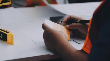 Mimarlar takımı, mühendisler mimari planları gözden geçirmek için birlikte çalışıyorlar. Planları inceliyor, bina planlarını not alıyor. Ofis ortamında olması muhtemel. Tasarım projesi için işbirliği anahtarı. Resim