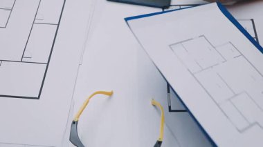 Mimarlar takımı, mühendisler mimari planları gözden geçirmek için birlikte çalışıyorlar. Planları inceliyor, bina planlarını not alıyor. Ofis ortamında olması muhtemel. Tasarım projesi için işbirliği anahtarı. Resim