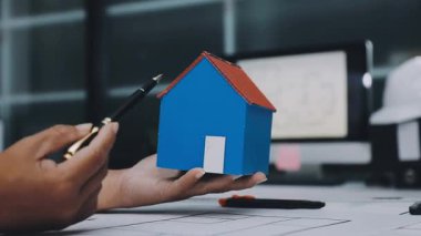 Mimarlar takımı, mühendisler mimari planları gözden geçirmek için birlikte çalışıyorlar. Planları inceliyor, bina planlarını not alıyor. Ofis ortamında olması muhtemel. Tasarım projesi için işbirliği anahtarı. Resim