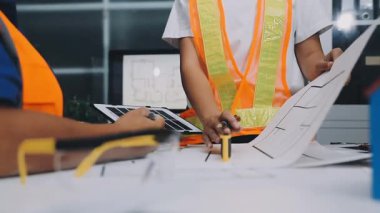 Mimarlar takımı, mühendisler mimari planları gözden geçirmek için birlikte çalışıyorlar. Planları inceliyor, bina planlarını not alıyor. Ofis ortamında olması muhtemel. Tasarım projesi için işbirliği anahtarı. Resim