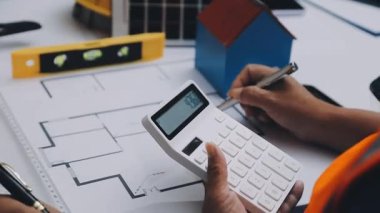 Mimarlar takımı, mühendisler mimari planları gözden geçirmek için birlikte çalışıyorlar. Planları inceliyor, bina planlarını not alıyor. Ofis ortamında olması muhtemel. Tasarım projesi için işbirliği anahtarı. Resim