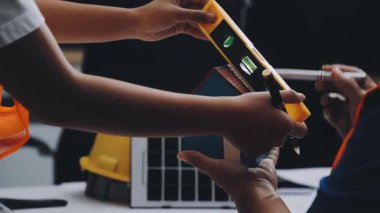 Mimarlar takımı, mühendisler mimari planları gözden geçirmek için birlikte çalışıyorlar. Planları inceliyor, bina planlarını not alıyor. Ofis ortamında olması muhtemel. Tasarım projesi için işbirliği anahtarı. Resim