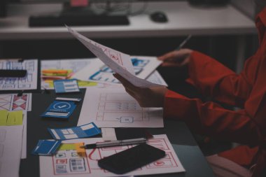 Uxui tasarımcılarından oluşan bir ekip bilgisayar ekranını işaret ederek ofiste yeni mobil uygulama tasarımını tartışıyor.