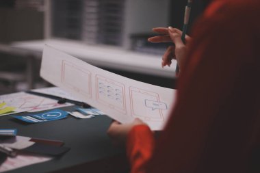 Uxui tasarımcılarından oluşan bir ekip bilgisayar ekranını işaret ederek ofiste yeni mobil uygulama tasarımını tartışıyor.