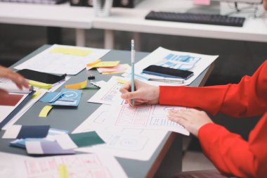 Uxui tasarımcılarından oluşan bir ekip bilgisayar ekranını işaret ederek ofiste yeni mobil uygulama tasarımını tartışıyor.