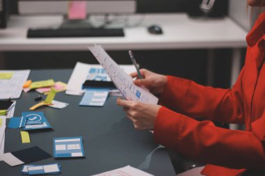 Uxui tasarımcılarından oluşan bir ekip bilgisayar ekranını işaret ederek ofiste yeni mobil uygulama tasarımını tartışıyor.